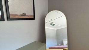 Ein Schlafzimmer mit einem Bett, einer Kommode, einem Spiegel und einem gerahmten Bild an der Wand.