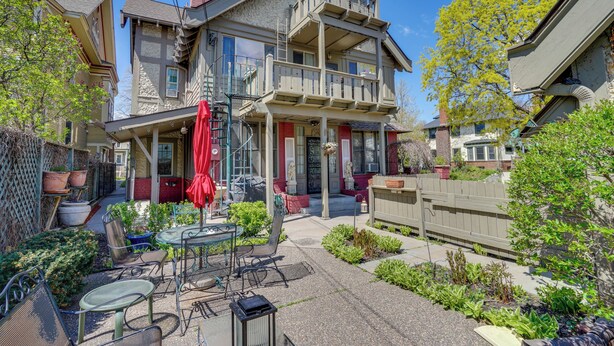 Une maison à deux étages avec un balcon, une terrasse dotée de mobilier d’extérieur et un jardin.