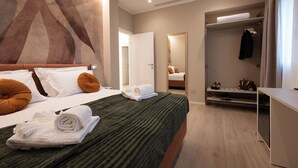 Ein modernes Hotelzimmer mit einem großen Bett, einem begehbaren Kleiderschrank und einem Spiegel.