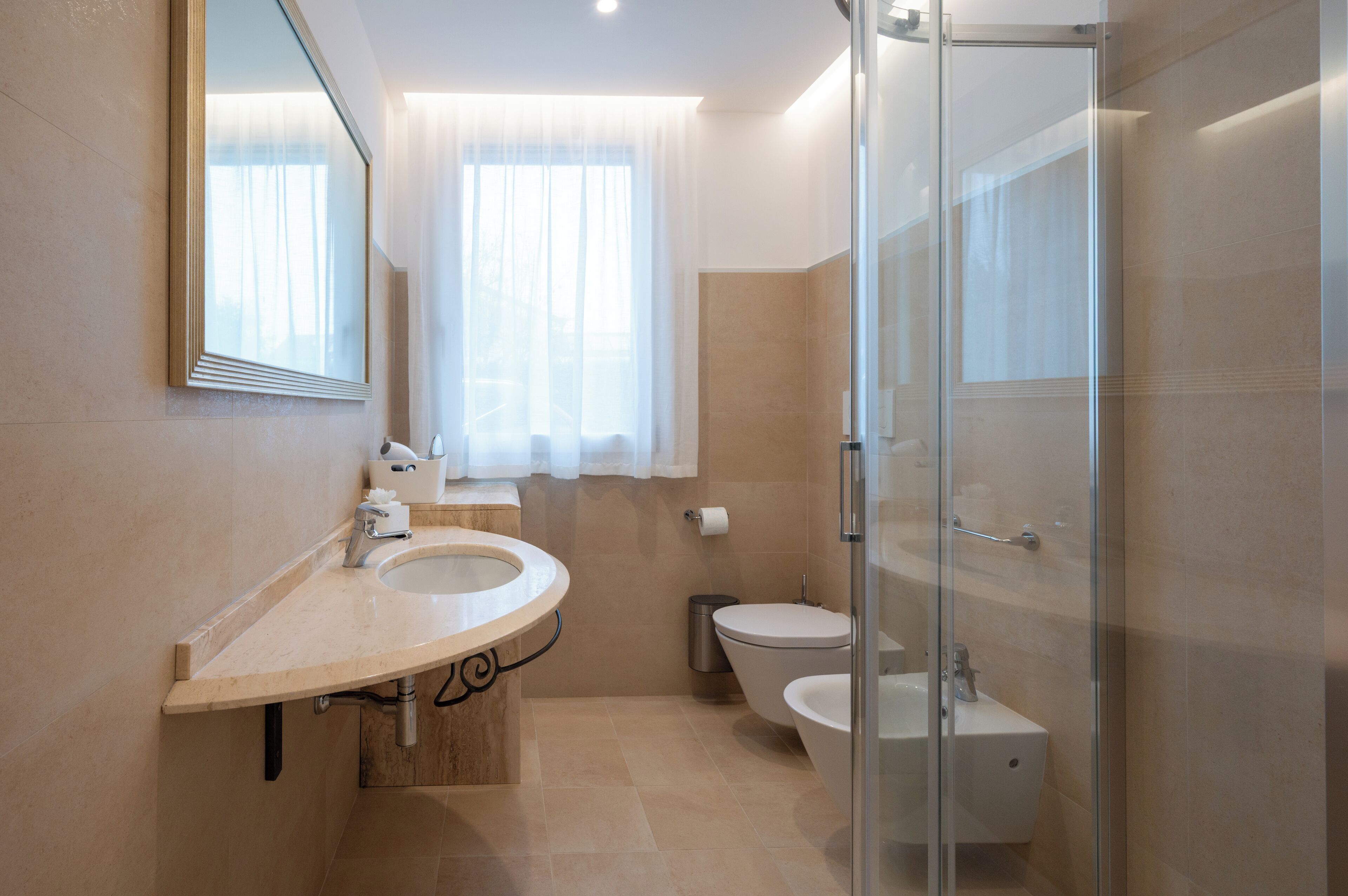 A modern bathroom with a sink, toilet, and glass shower enclosure.