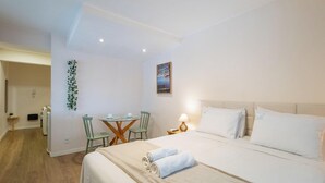 A hotel room with a bed, a desk with chairs, a lamp, and a painting on the wall. - Studio w/ Self Check-in in BSB Car0001 (Brasília)