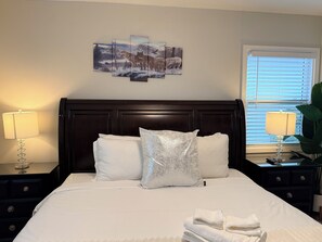 A bed with white linens, a dark wooden headboard, and a multi-panel artwork above. -  Relaxing Cozy Back House with Backyard (Upland)