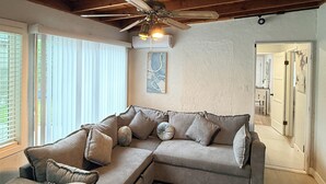 Een woonkamer met een modulaire bank, een plafondventilator en een kamerbreed tapijt.