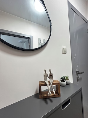Um banheiro com um espelho, uma escultura de madeira e um vaso com planta no balcão.