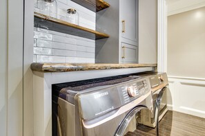 Een moderne keuken met een ingebouwde wasmachine en droger, roestvrijstalen apparatuur en een houten aanrecht.