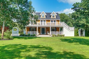 A two-story house with a front porch, a staircase, and a well-maintained lawn. - Summer Beach Pass: Wooded Martha's Vineyard Escape (Vineyard Haven)