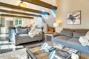 Een ruime woonkamer met een hoge plafond, een eettafel en een keuken op de achtergrond.