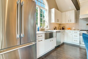 Een moderne keuken met roestvrijstalen apparatuur, witte keukenkastjes en een groot raam voor natuurlijk licht.