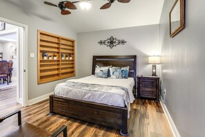 A bedroom with a wooden bed, a nightstand, a wall-mounted shelf, and a ceiling fan. - 1/2 Mi to Hospitals: Updated Baton Rouge Stay (Baton Rouge)