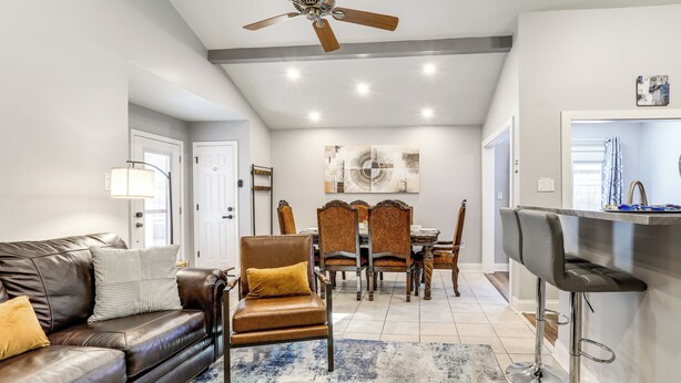 A modern living room with a leather sofa, a coffee table, and a dining area with a chandelier. - 1/2 Mi to Hospitals: Updated Baton Rouge Stay (Baton Rouge)
