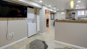 A modern kitchen with a large TV, a built-in washer and dryer, a kitchen island, and a blender. - Remote-Work Hub! DC Unit 1 Mi to Rock Creek Park (Washington)