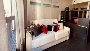 A living room with a sofa, pillows, a black cabinet, and artwork on the wall. - Paris 4U Studio (Paris)