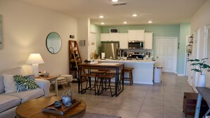 Una sala de estar moderna con un sofá, una mesa de centro y un comedor con cocina al fondo.