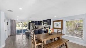 A modern kitchen with dark cabinets, a wooden dining table, and a bench. - Spacious 5-bedroom/4-bathroom house. Less than 1 block to beach! Free Wine! (Fort Myers Beach)