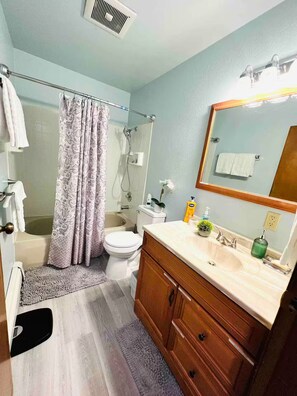 A bathroom with a shower, toilet, sink, and mirror.