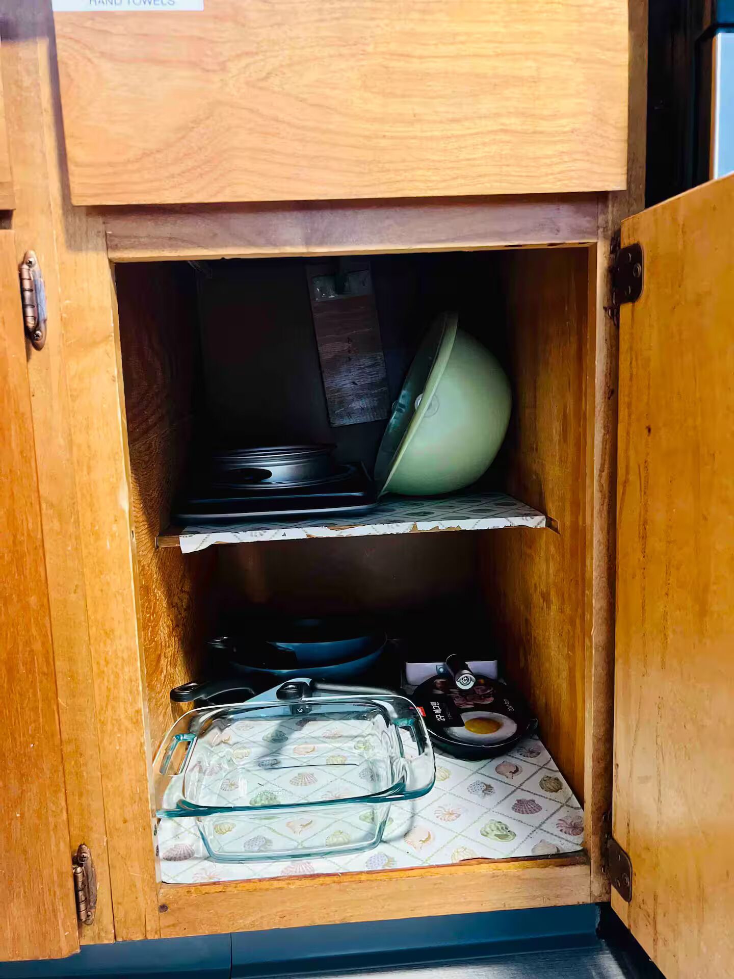 Un meuble en bois muni d’un égouttoir à vaisselle en verre et d’un récipient en plastique.