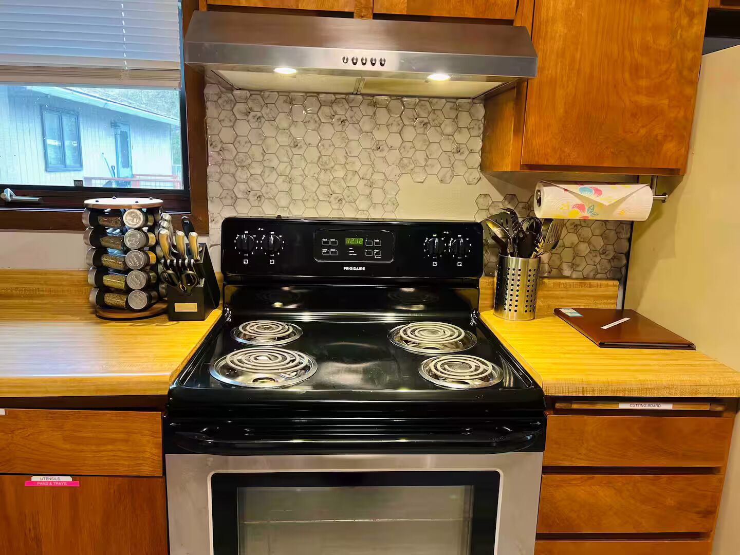 Una cocina con estufa negra, microondas y armarios de madera.