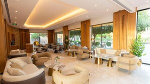 Un hall d’hôtel moderne doté d’un vaste espace salon, de grandes fenêtres et d’un design épuré et contemporain.