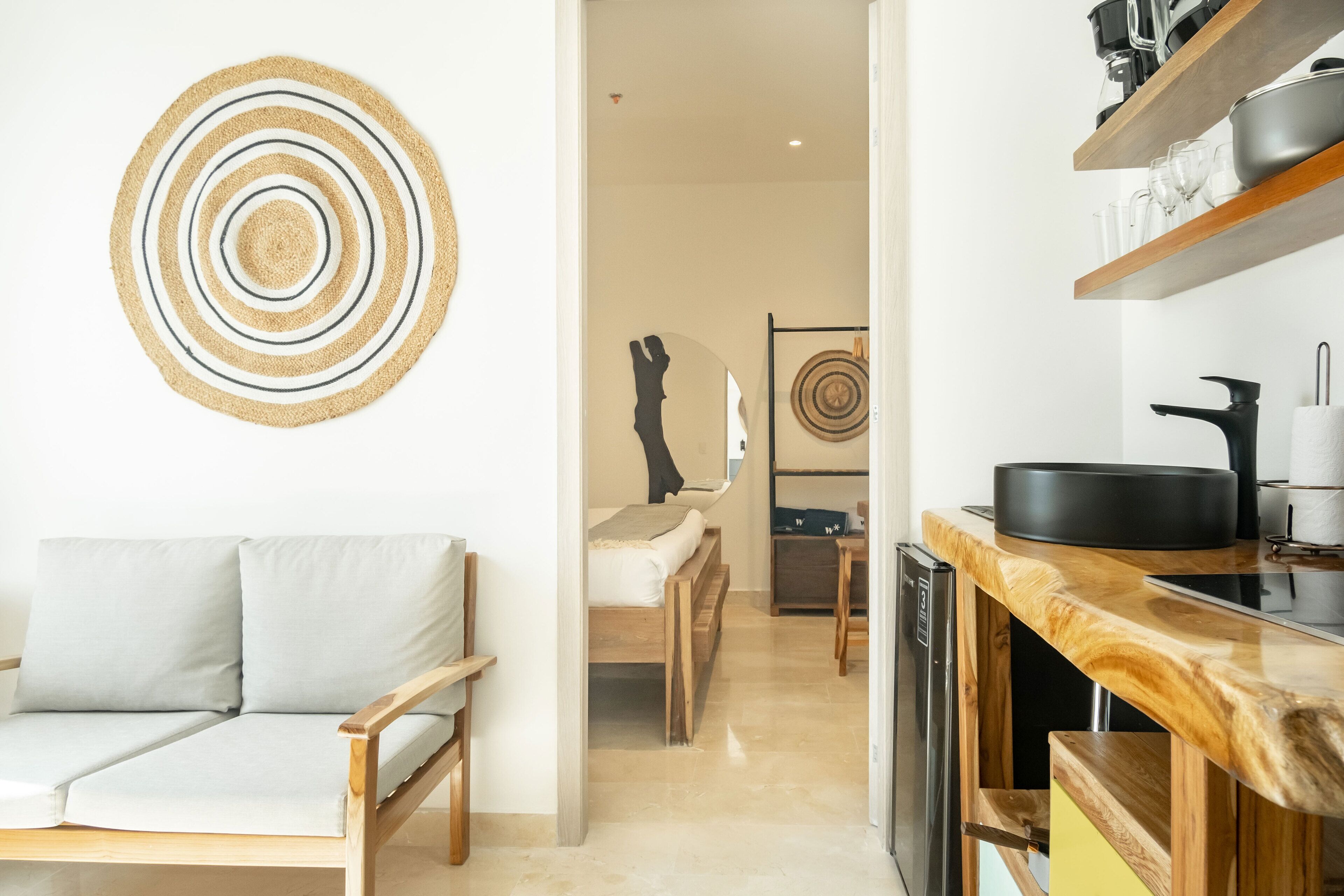 Une cuisine moderne avec des étagères en bois, un coin repas avec un canapé et un couloir menant à une chambre.