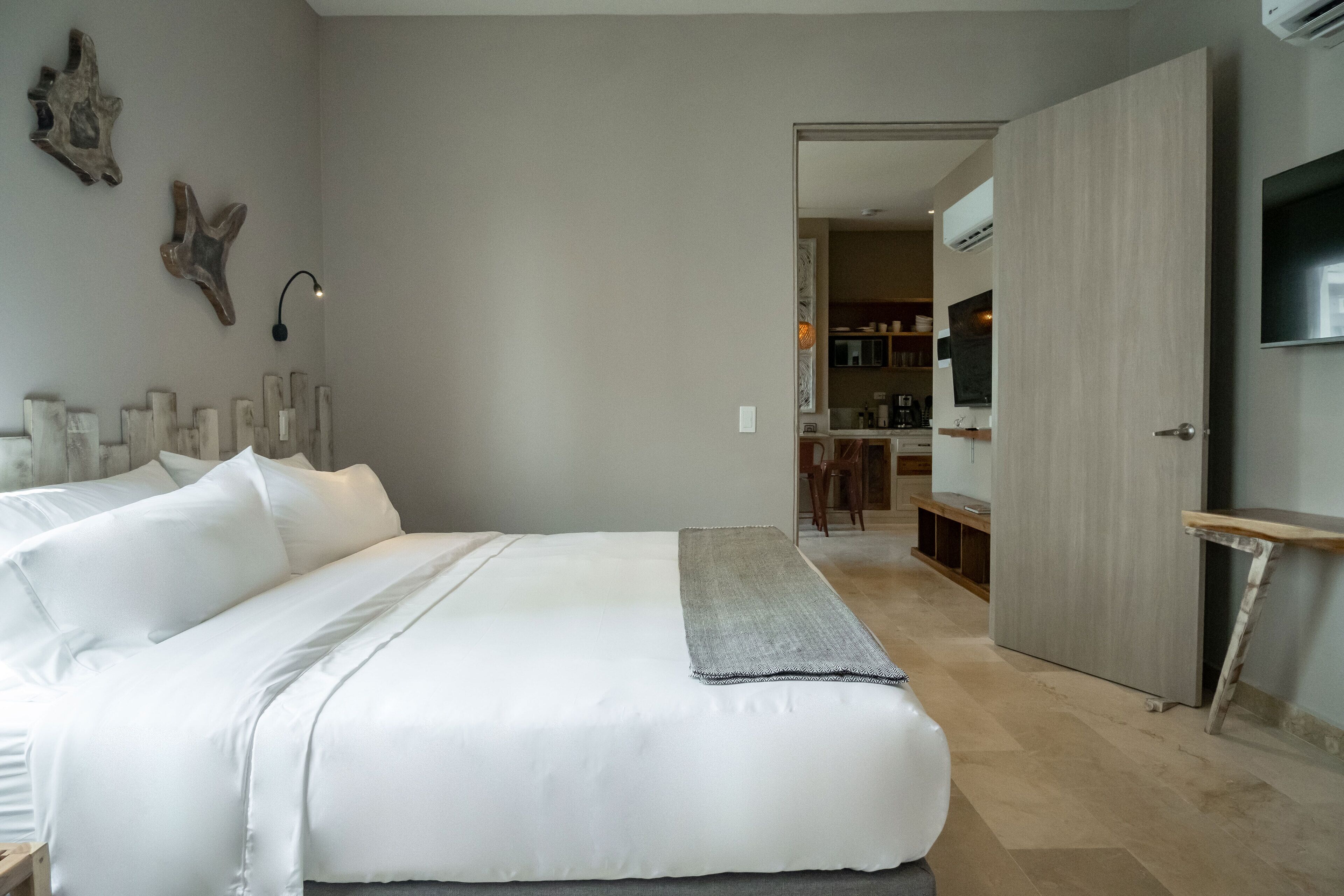 A bedroom with a large bed, a bedside table, a TV, and a wooden door.