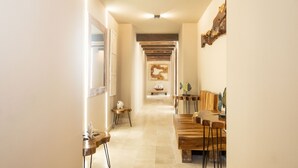 A hallway with wooden benches and tables, a ship model, and wall art. - Mega by Wynwood House (Cartagena)