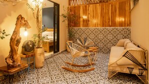 A cozy room with a patterned floor, a wooden wall, a sofa, and a rocking chair. - Mega by Wynwood House (Cartagena)
