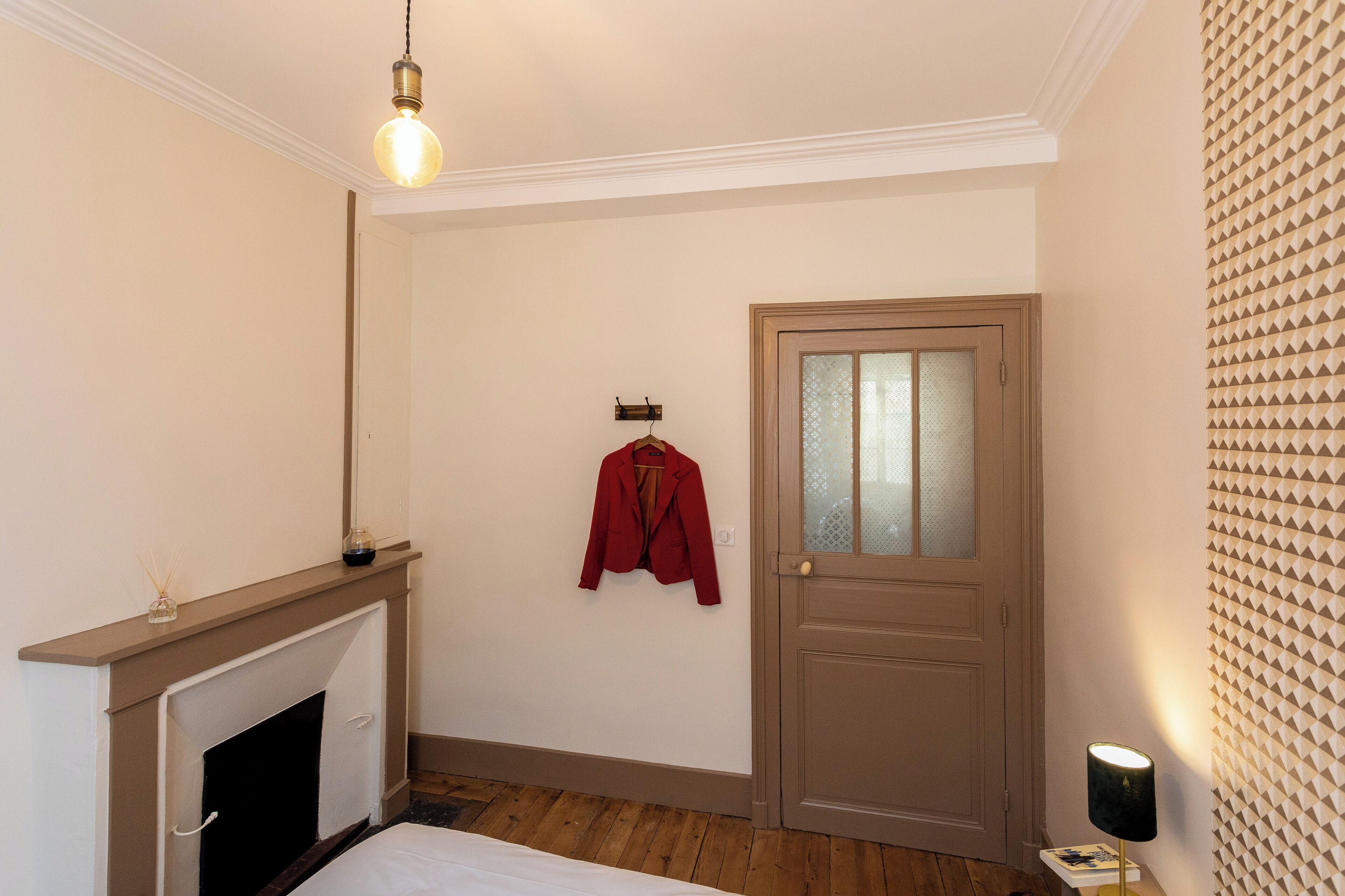 A room with a fireplace, a door with frosted glass panels, and a wall with a geometric pattern.
