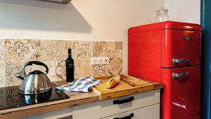 A kitchen with a red refrigerator, a kettle, a bottle, a loaf of bread, and a cutting board. - 🏡 Large charming gîte in Fontevraud - Warm winter stays (6 to 12 pers) (Fontevraud-l'Abbaye)