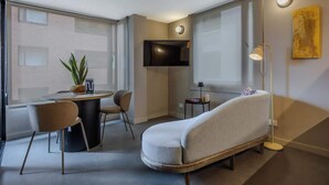 A modern living room with a sofa, a dining table, chairs, a TV mounted on the wall, and a floor lamp. - NOK Cozy 1BR Apartment with Terrace at Bogota (Bogotá)