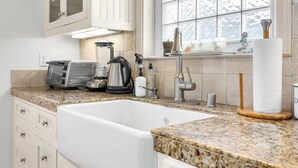 Una cocina con un lavamanos blanco, encimera de granito y electrodomésticos de acero inoxidable.