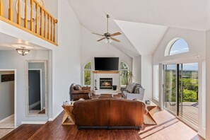 A spacious living room with a fireplace, leather sofa, and a large TV. - Canyon Oasis - Spectacular Views with Hot Tub (Holladay)