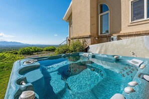 Un bain à remous avec vue sur les montagnes et une maison.