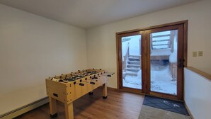 A room with a wooden foosball table, a sliding glass door leading outside, and a wooden floor. - LAKEFRONT 2-bedroom Chateau Getaway at Whitecap Mountains Resort Unit 3 (Upson)