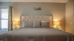 Ein Schlafzimmer mit einem großen Bett, zwei Nachttischlampen und einem an der Wand befestigten Schild mit der Aufschrift 'Cuddle'.