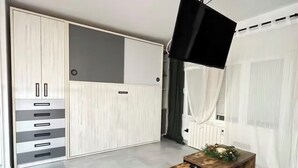 A modern room with a large wardrobe, a flat-screen TV mounted on the wall, and a wooden coffee table. - Madrid comfort suites (Aluche)