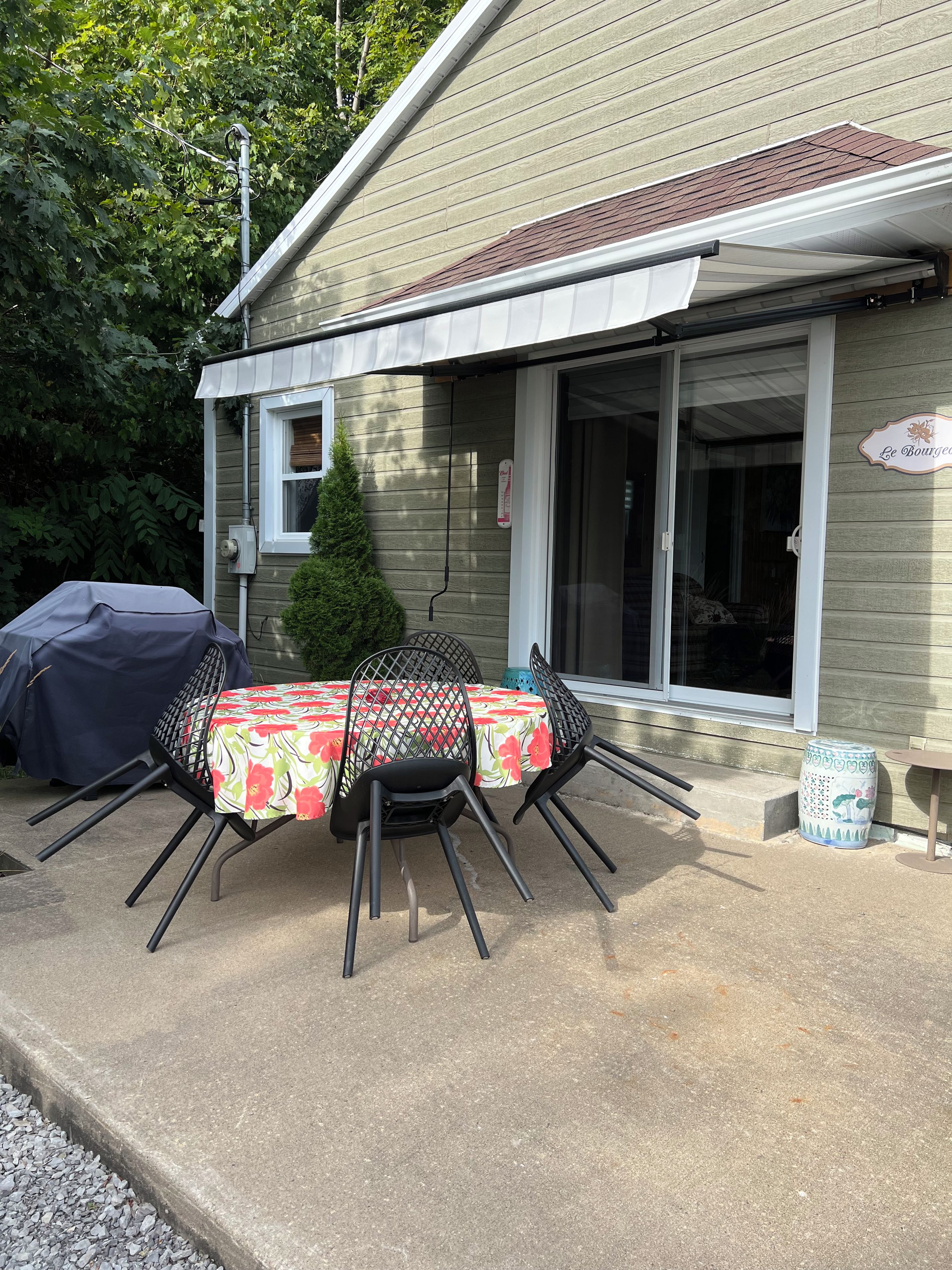 Une terrasse extérieure avec une table et des chaises, un barbecue et un espace abrité.