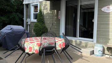 Une terrasse extérieure avec une table et des chaises, un barbecue et un espace abrité.
