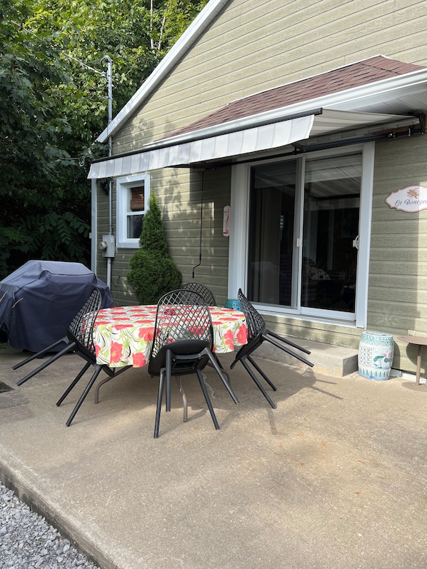 An outdoor patio with a table and chairs, a barbecue grill, and a covered area.