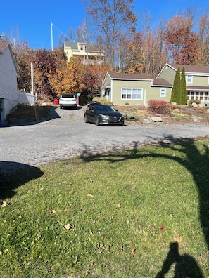 A residential driveway with a parked car, a mailbox, and houses in the background.