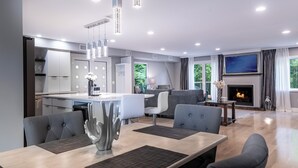 Una sala de estar moderna con chimenea, un comedor con una mesa grande y sillas, y una cocina con gabinetes blancos y una isla integrada.