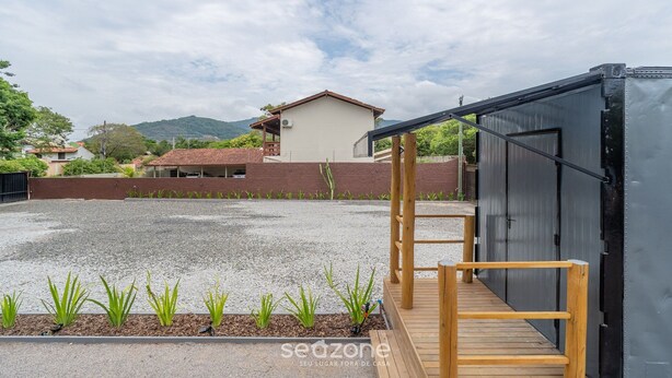 Un edificio con un cortile in ghiaia, un pontile in legno e una struttura metallica.