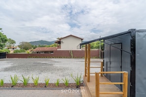 Un edificio con un patio de grava, una terraza de madera y una estructura metálica.
