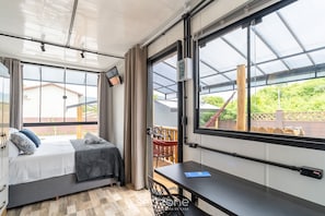 A bedroom with a bed, a desk, and a large window. - Chalet 200m the Beach in Florianopolis Scj0007 (Florianópolis)