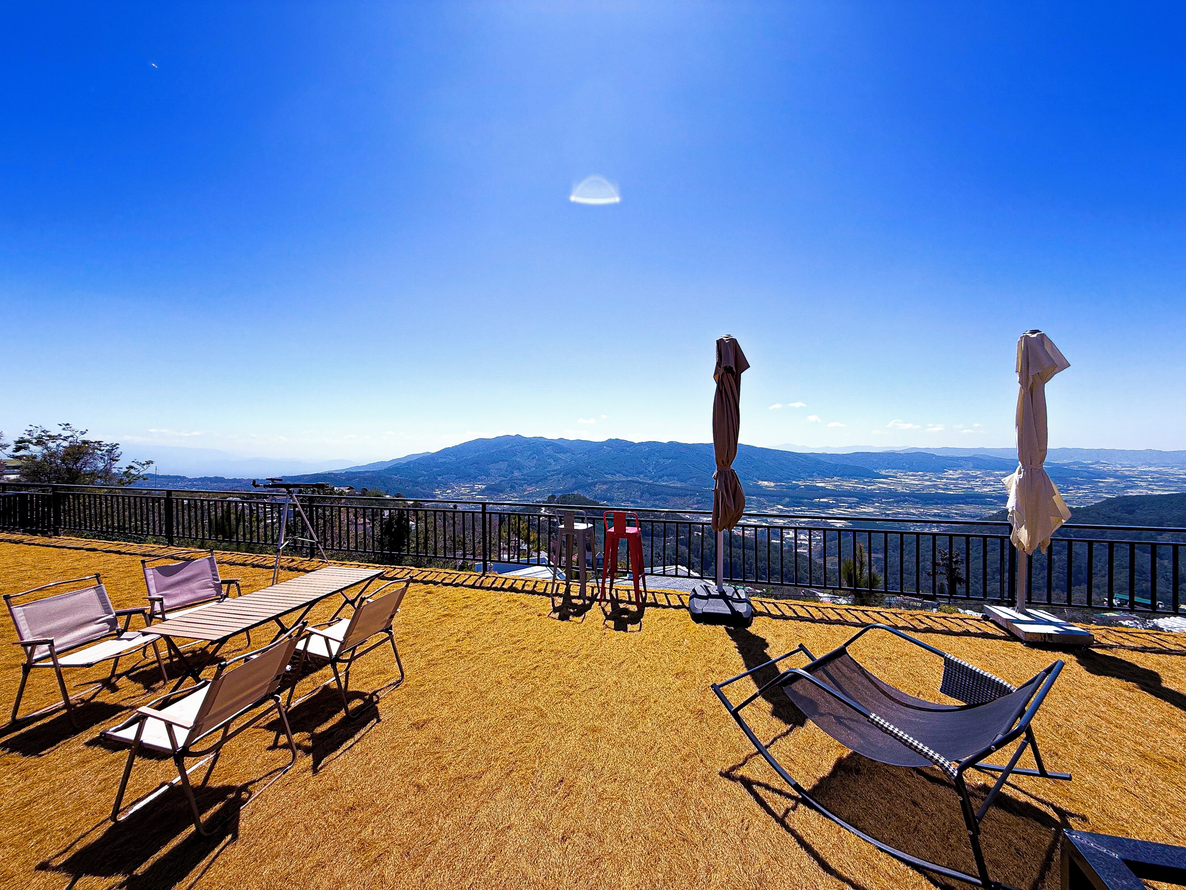 A terrace with outdoor seating, a view of distant mountains, and a clear sky.