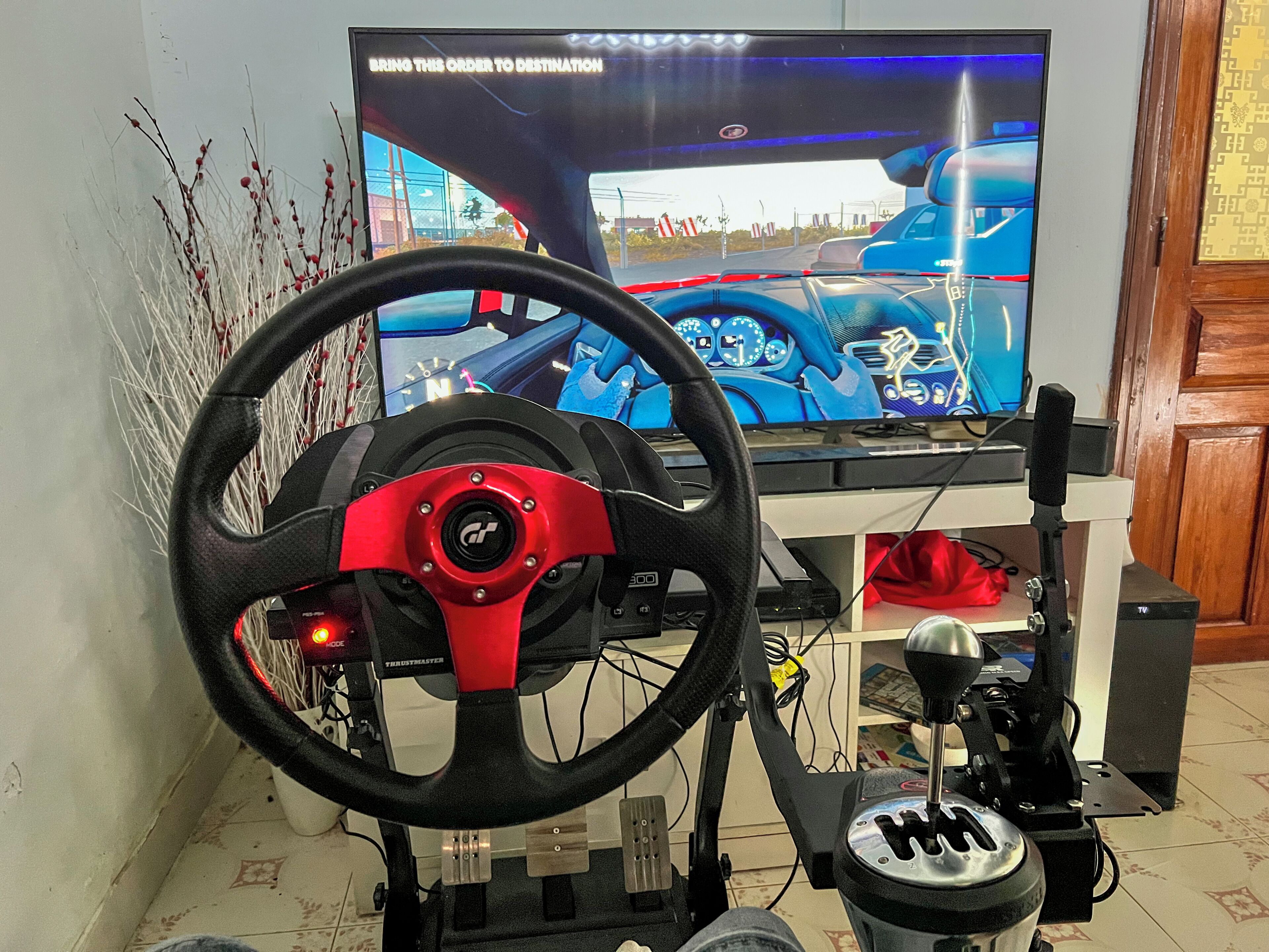 En speluppsättning för racingspel med en ratt, pedaler och en tv-skärm som visar racingspelet.