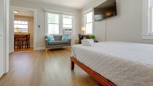Un dormitorio con cama, ventilador de techo, televisor y ventana.