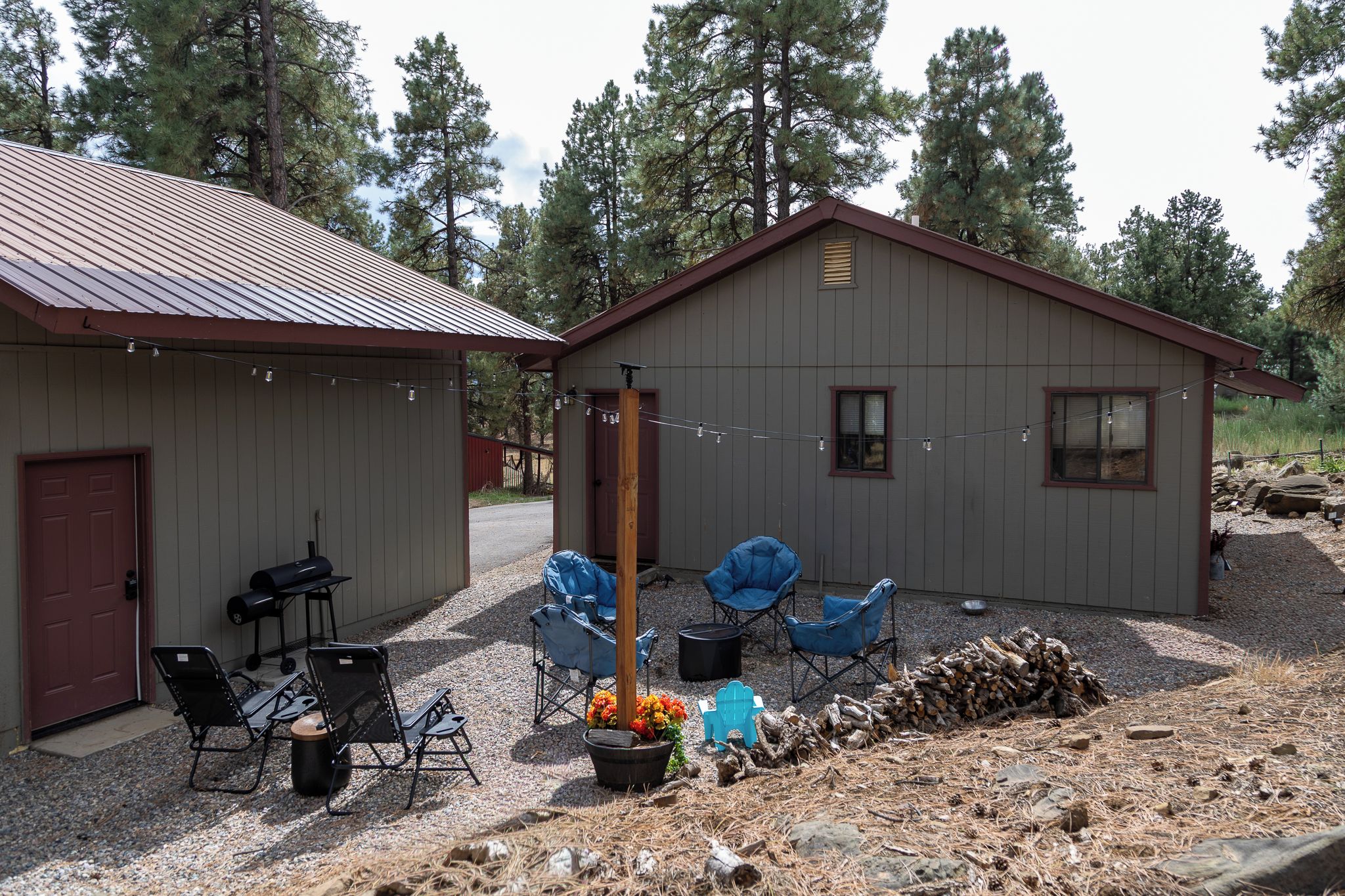 Une cabane avec une allée en gravier, un barbecue et un espace salon extérieur.