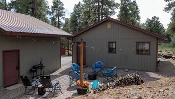 Une cabane avec une allée en gravier, un barbecue et un espace salon extérieur.
