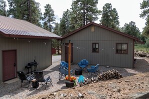 A cabin with a gravel driveway, a barbecue grill, and outdoor seating.