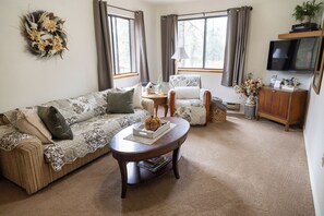 A living room with a sofa, armchair, coffee table, and a television.